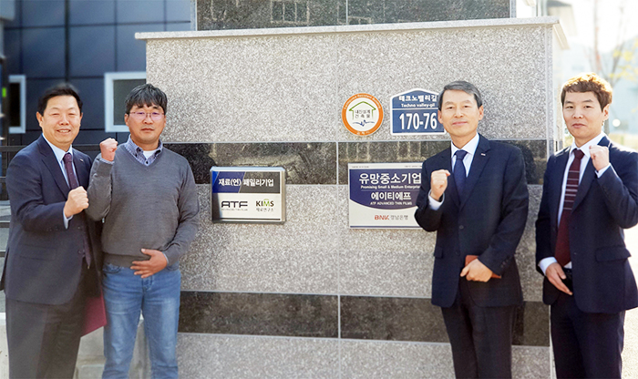 ▲ BNK경남은행 김영원 상무(사진 오른쪽에서 2번째)와 에이티에프 박창하 대표이사(왼쪽에서 2번째)가 유망중소기업 현판식을 갖고 있다.